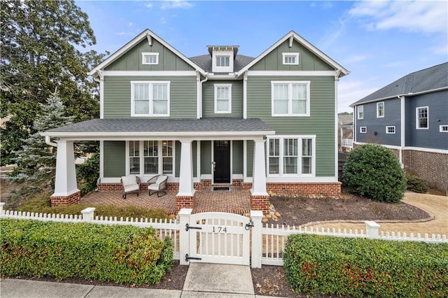 craftsman inspired home featuring a fenced front yard, a gate, a porch, and board and batten siding