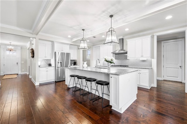 kitchen with dark wood finished floors, wall chimney exhaust hood, beamed ceiling, stainless steel refrigerator with ice dispenser, and a sink