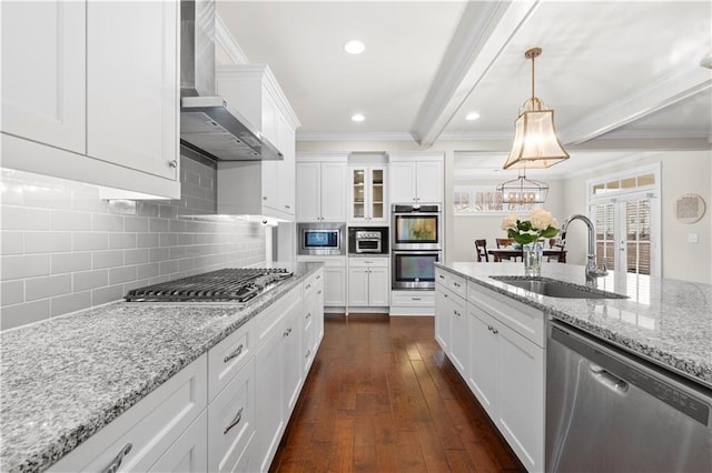 kitchen with beam ceiling, dark wood finished floors, stainless steel appliances, a sink, and wall chimney exhaust hood