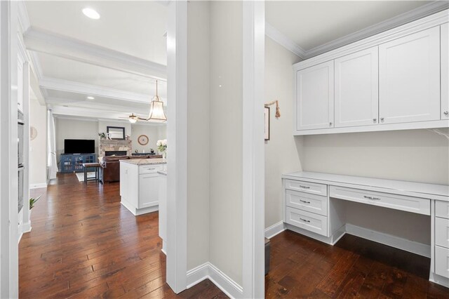 office area with a fireplace, dark wood finished floors, crown molding, and built in study area