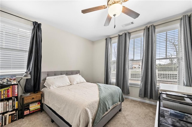 bedroom featuring light colored carpet, visible vents, baseboards, and multiple windows