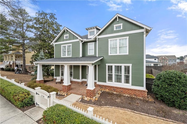 view of front of property featuring a porch, board and batten siding, a fenced front yard, and a gate