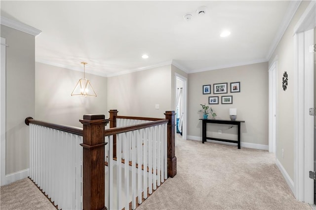 hall with a notable chandelier, carpet floors, an upstairs landing, baseboards, and ornamental molding