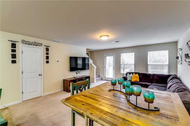 living room featuring baseboards, stairs, visible vents, and light colored carpet