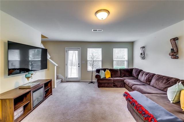 carpeted living area featuring visible vents, stairway, and baseboards