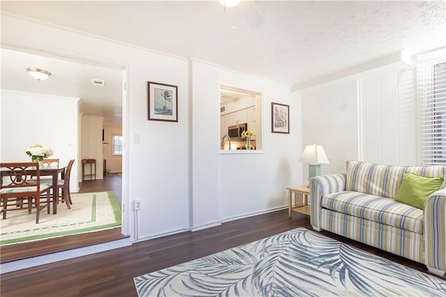 living room featuring ceiling fan, dark wood-type flooring, and a textured ceiling