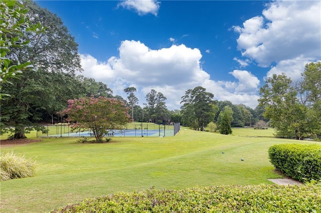 view of home's community featuring tennis court and a yard