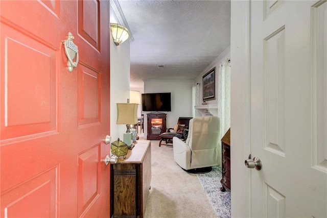 foyer with light carpet, a textured ceiling, and a fireplace