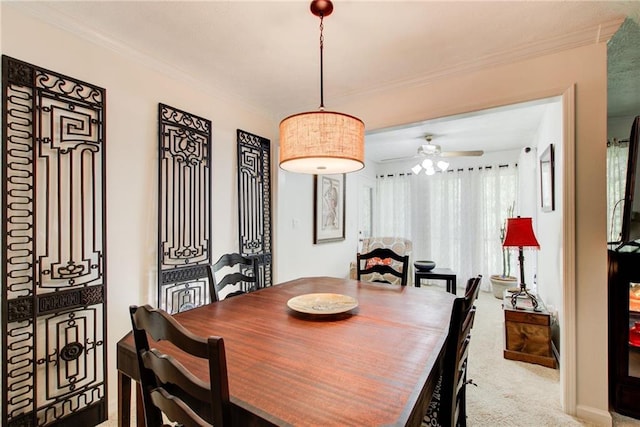 carpeted dining area with crown molding and ceiling fan