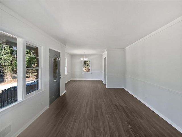 empty room with dark wood-type flooring and a notable chandelier