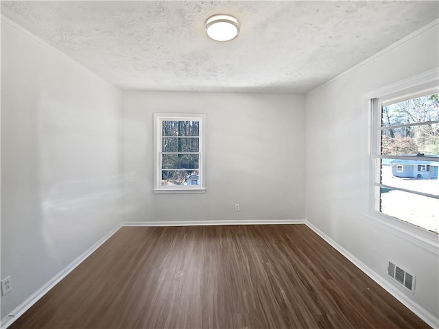 spare room featuring dark hardwood / wood-style flooring and a textured ceiling