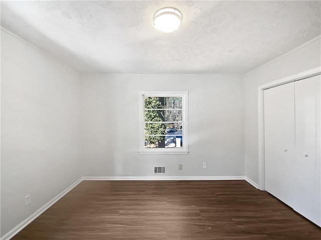 unfurnished bedroom featuring dark hardwood / wood-style floors, a textured ceiling, and a closet