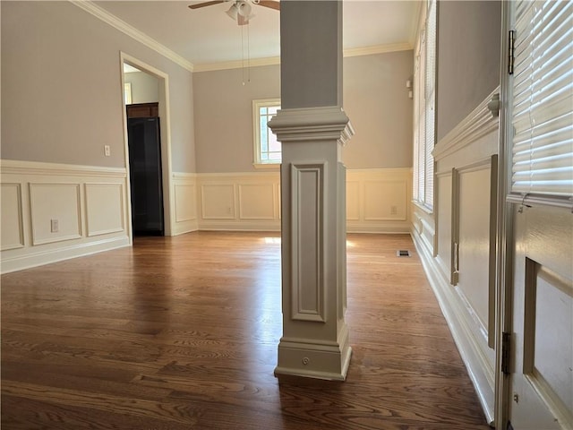 unfurnished living room with crown molding, ceiling fan, dark wood-type flooring, and ornate columns