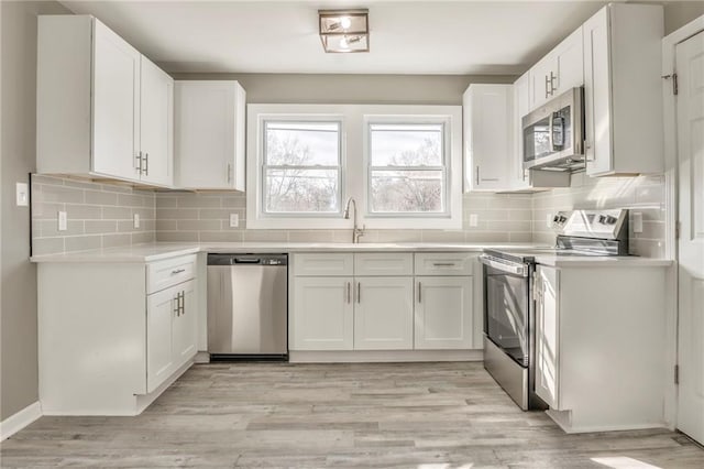 kitchen featuring stainless steel appliances, light wood-type flooring, light countertops, and white cabinetry