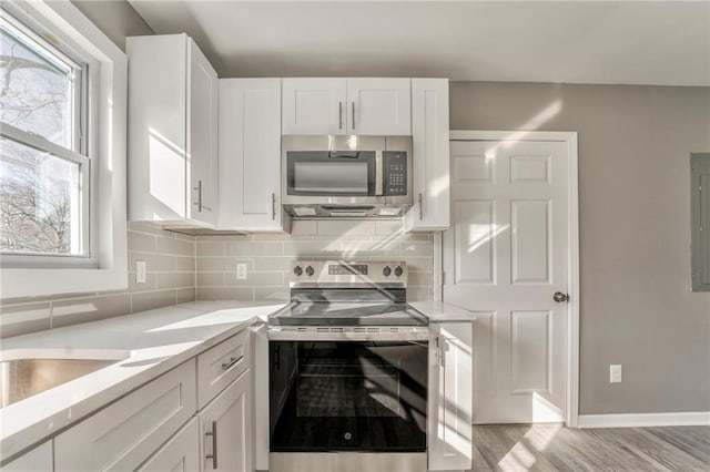 kitchen with appliances with stainless steel finishes, white cabinets, and a wealth of natural light