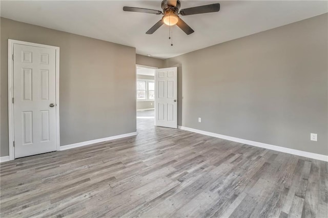 unfurnished room featuring baseboards, a ceiling fan, and light wood-style floors