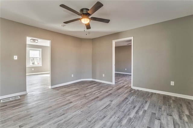 spare room featuring light wood-type flooring, baseboards, visible vents, and ceiling fan