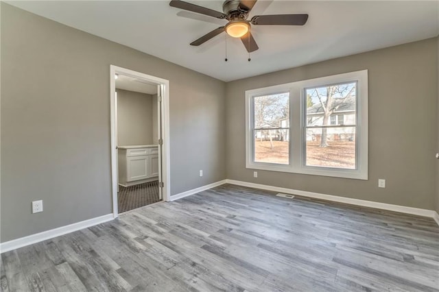 unfurnished bedroom featuring ceiling fan, light wood-type flooring, connected bathroom, and baseboards