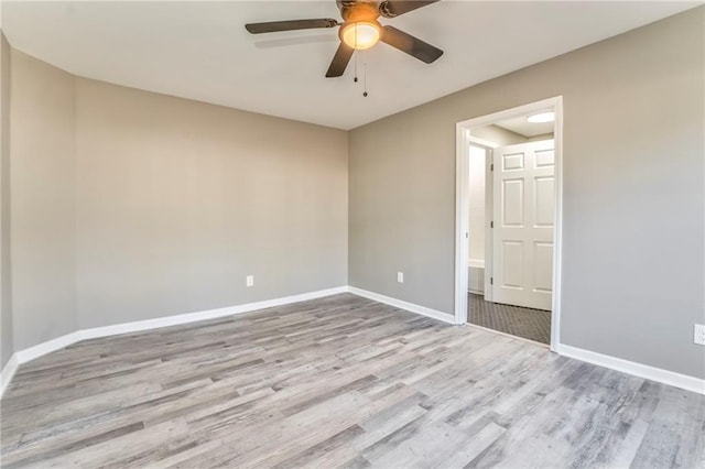 empty room with a ceiling fan, light wood-style flooring, and baseboards