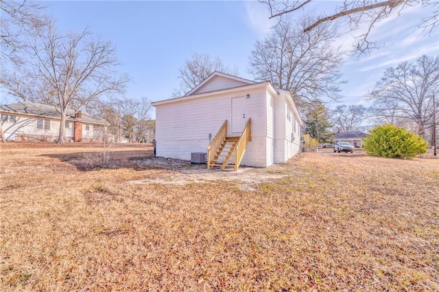 exterior space with entry steps, a yard, and central air condition unit