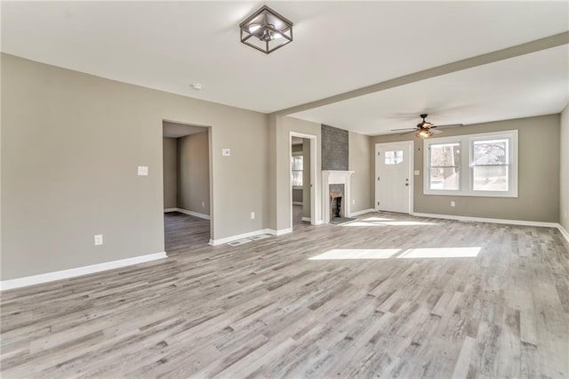 unfurnished living room with a brick fireplace, light wood-style flooring, baseboards, and a ceiling fan