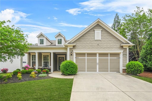 craftsman house featuring a porch, an attached garage, driveway, and a front lawn