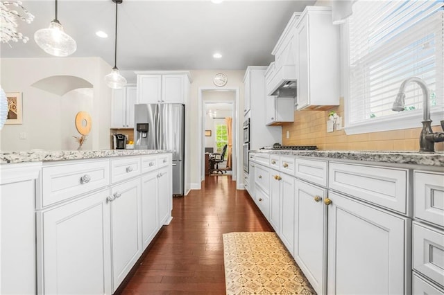 kitchen with backsplash, light stone countertops, a sink, white cabinets, and stainless steel appliances