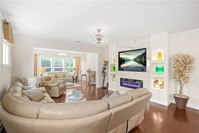 living room featuring baseboards, dark wood-style flooring, a chandelier, and a premium fireplace