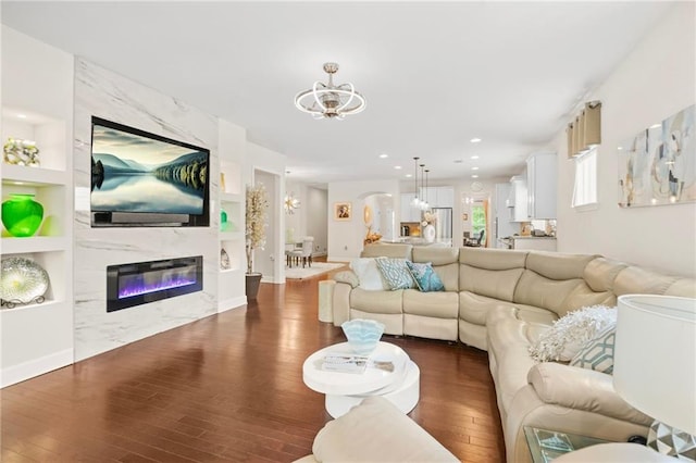 living area featuring an inviting chandelier, built in shelves, and wood finished floors