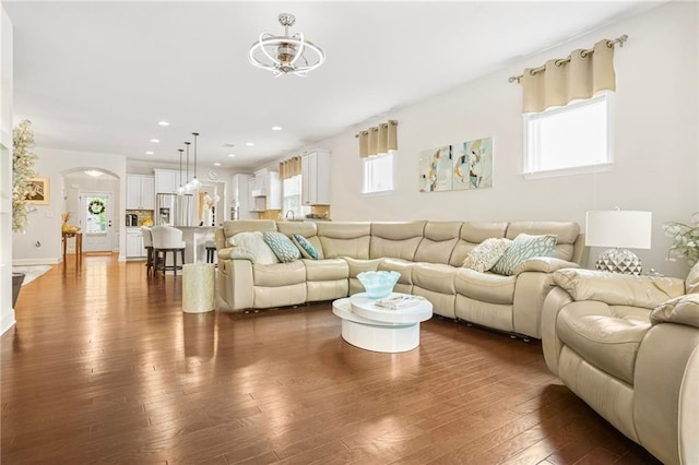 living room with a healthy amount of sunlight, arched walkways, ceiling fan, and dark wood-style floors
