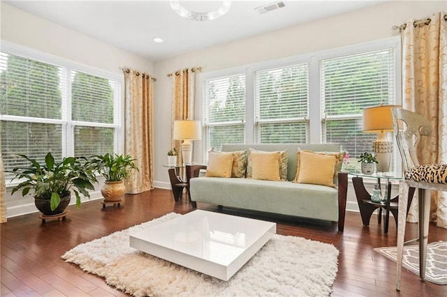 living area featuring plenty of natural light, wood-type flooring, baseboards, and visible vents
