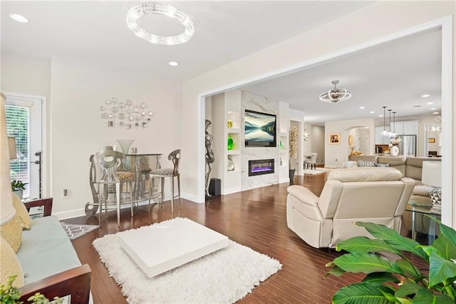 living room with baseboards, arched walkways, wood finished floors, and a premium fireplace