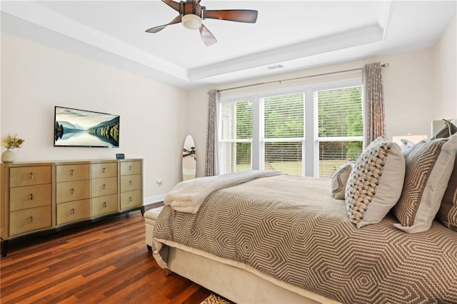 bedroom with a raised ceiling, visible vents, ceiling fan, and dark wood-type flooring
