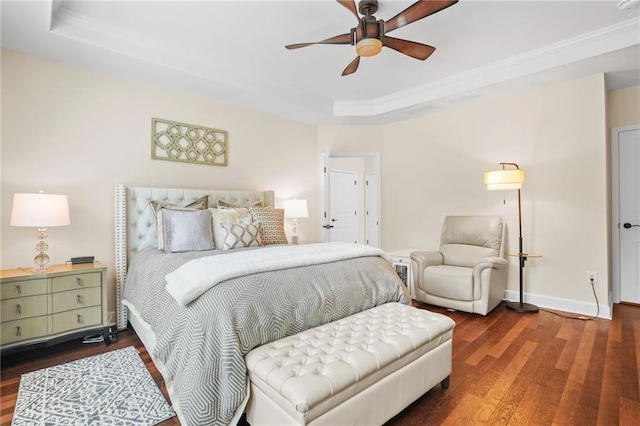 bedroom featuring a raised ceiling, ornamental molding, baseboards, and wood finished floors