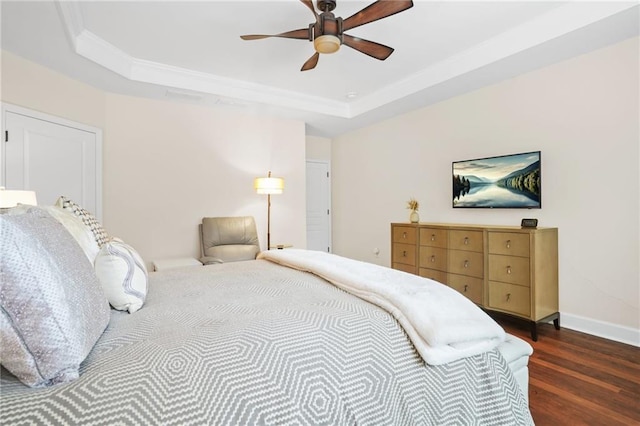 bedroom featuring baseboards, ornamental molding, a tray ceiling, and wood finished floors