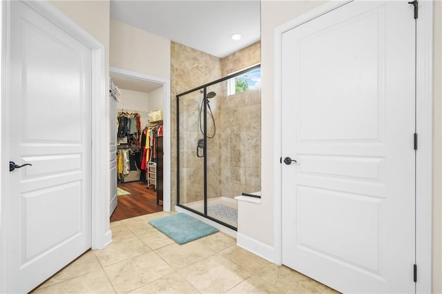 full bathroom with tile patterned floors, a shower stall, and a walk in closet