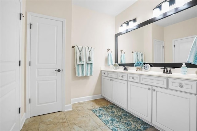 bathroom with a sink, baseboards, and double vanity