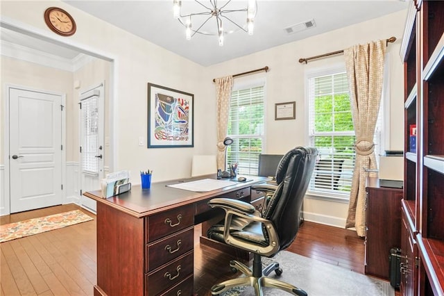 office space featuring visible vents, baseboards, a notable chandelier, ornamental molding, and hardwood / wood-style floors
