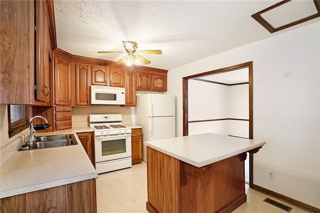 kitchen featuring white appliances, a sink, light countertops, brown cabinetry, and a ceiling fan