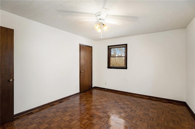 spare room with baseboards, ceiling fan, and a textured ceiling