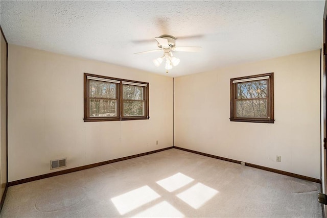 carpeted spare room featuring plenty of natural light, ceiling fan, baseboards, and a textured ceiling