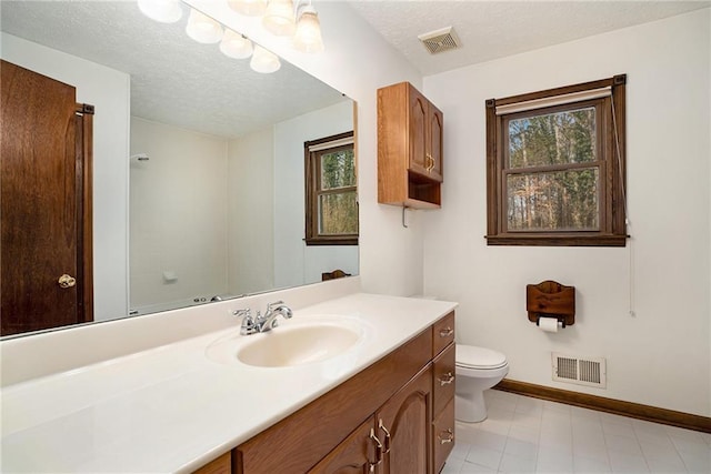 bathroom featuring baseboards, healthy amount of natural light, toilet, vanity, and a textured ceiling