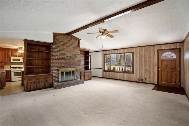 unfurnished living room featuring a textured ceiling, healthy amount of natural light, wooden walls, ceiling fan, and a brick fireplace