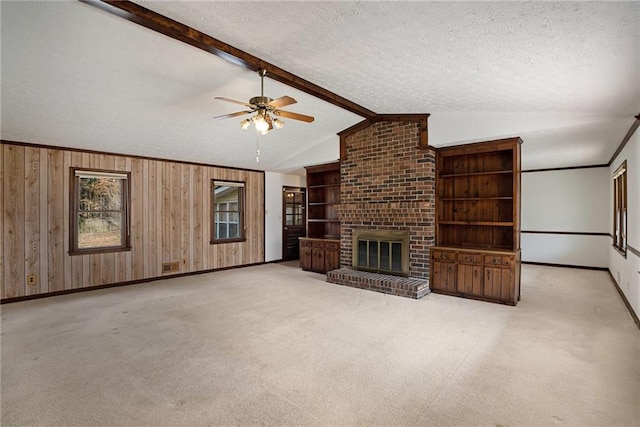 unfurnished living room featuring baseboards, ceiling fan, carpet, wood walls, and a fireplace