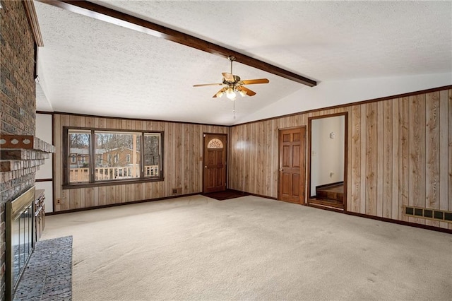 unfurnished living room featuring a brick fireplace, ceiling fan, wood walls, carpet, and a textured ceiling