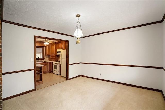 unfurnished room featuring a sink, light carpet, baseboards, ornamental molding, and a ceiling fan