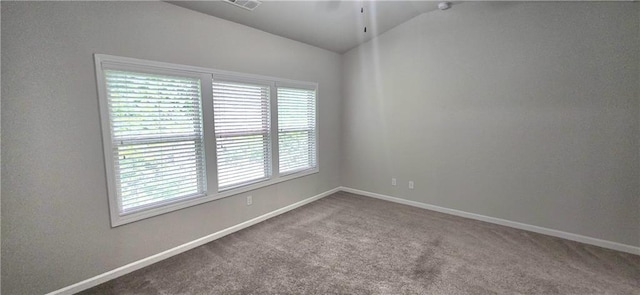 carpeted empty room featuring vaulted ceiling, baseboards, and visible vents