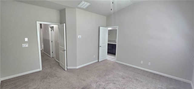 unfurnished bedroom with visible vents, vaulted ceiling, carpet flooring, connected bathroom, and baseboards