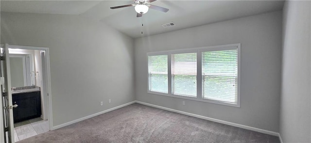 carpeted spare room featuring vaulted ceiling, ceiling fan, baseboards, and visible vents