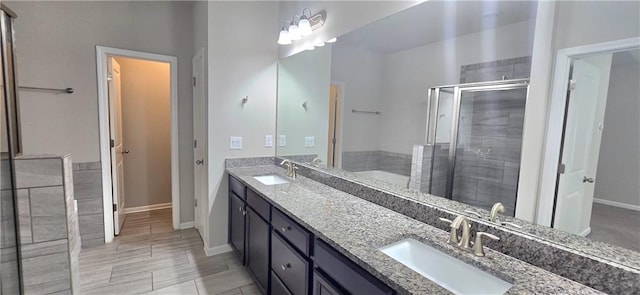 full bath featuring a sink, double vanity, baseboards, and a shower stall